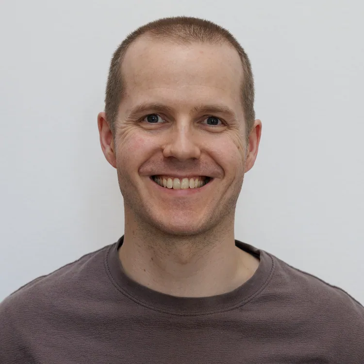 Man (Jonas) with short hair, shaved, smiling and wearing an old sweater